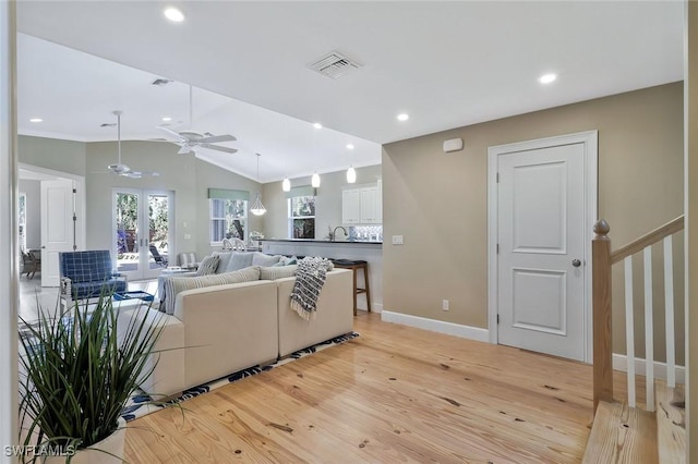 living room with recessed lighting, visible vents, vaulted ceiling, french doors, and light wood finished floors