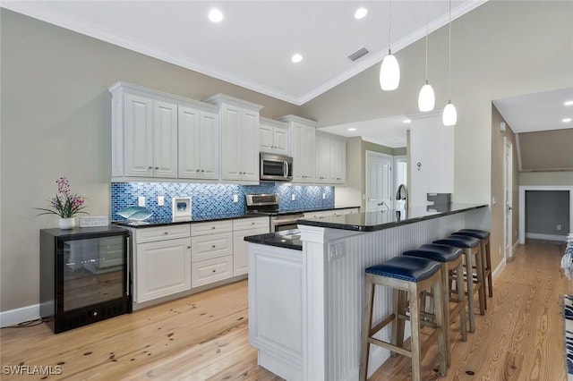 kitchen with crown molding, dark countertops, visible vents, appliances with stainless steel finishes, and beverage cooler