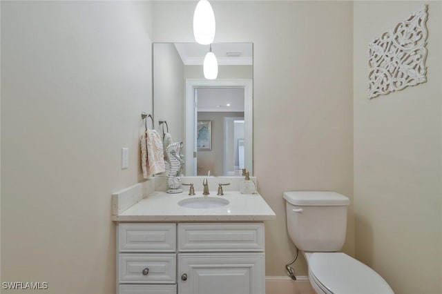 half bathroom featuring toilet, baseboards, ornamental molding, and vanity