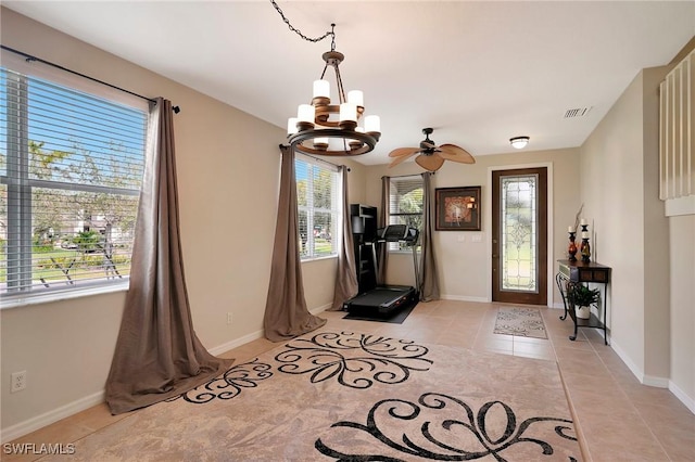interior space with ceiling fan with notable chandelier, baseboards, visible vents, and light tile patterned floors