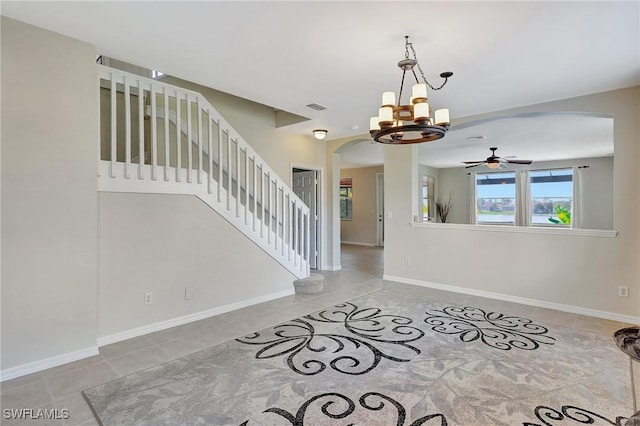 interior space with arched walkways, baseboards, visible vents, ceiling fan with notable chandelier, and stairs