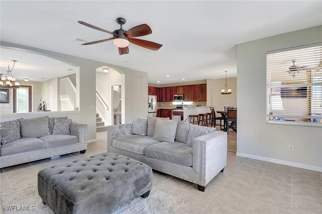 living room with visible vents, light tile patterned floors, arched walkways, baseboards, and stairs