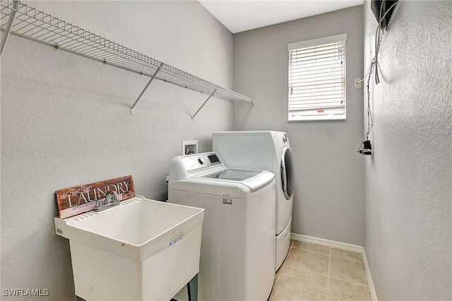 laundry room with a sink, baseboards, washer and dryer, laundry area, and light tile patterned floors