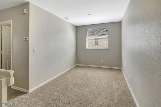 unfurnished room with baseboards, visible vents, and light colored carpet