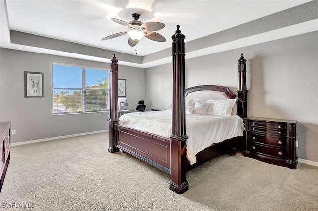carpeted bedroom featuring ceiling fan, baseboards, and a raised ceiling