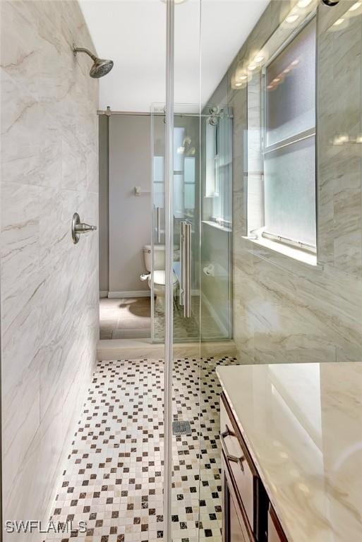 full bathroom with tile walls, vanity, a shower stall, and toilet