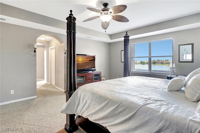carpeted bedroom with arched walkways, baseboards, and ceiling fan