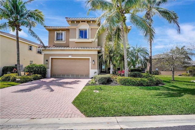 mediterranean / spanish-style home featuring stucco siding, a tile roof, a garage, and decorative driveway