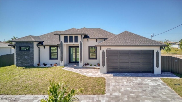 view of front of house with decorative driveway, stucco siding, an attached garage, fence, and a front lawn