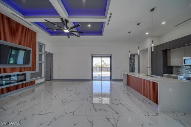 kitchen with modern cabinets, stainless steel microwave, coffered ceiling, and open floor plan