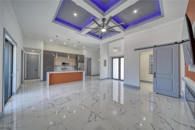 kitchen featuring light countertops, stainless steel microwave, a barn door, open floor plan, and coffered ceiling