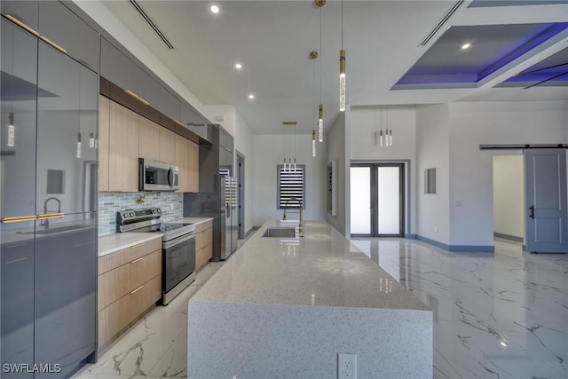 kitchen with a barn door, stainless steel appliances, marble finish floor, modern cabinets, and a center island with sink