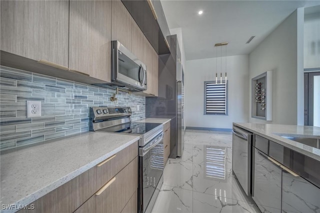 kitchen with marble finish floor, appliances with stainless steel finishes, light stone countertops, light brown cabinetry, and modern cabinets