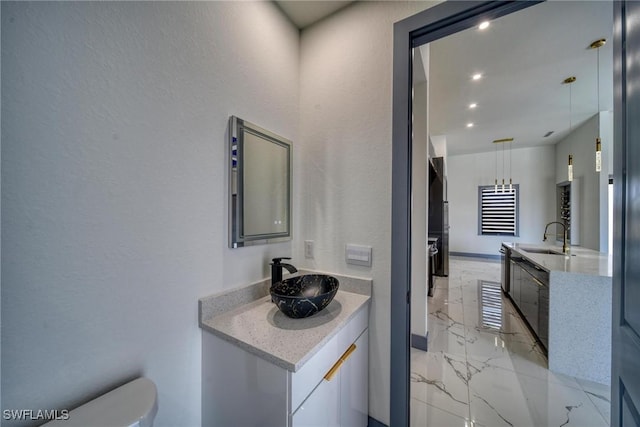 bathroom with toilet, marble finish floor, two vanities, and a sink