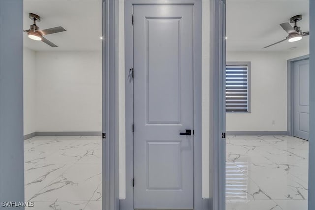 hallway featuring marble finish floor and baseboards