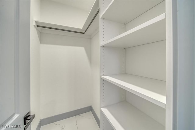 walk in closet featuring marble finish floor