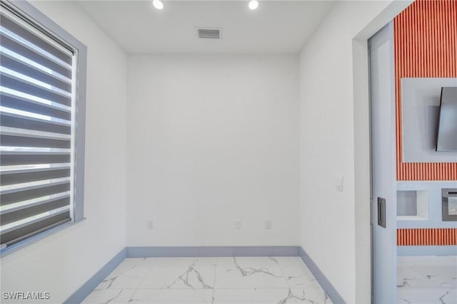 empty room with marble finish floor, visible vents, and baseboards