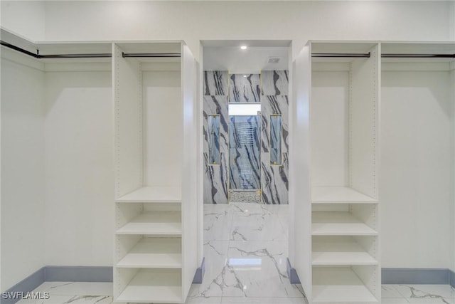 walk in closet featuring marble finish floor