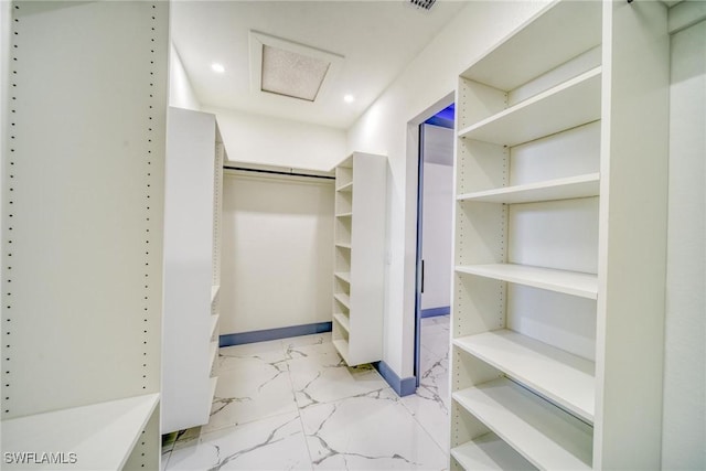 walk in closet featuring marble finish floor and attic access