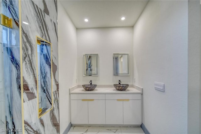 bathroom with double vanity, marble finish floor, baseboards, and a sink