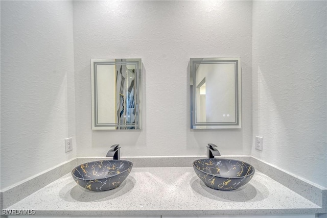 details with a textured wall, double vanity, and a sink