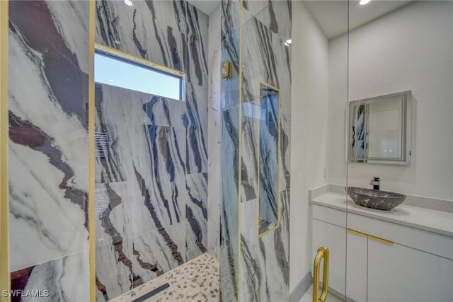 full bathroom featuring a marble finish shower and vanity