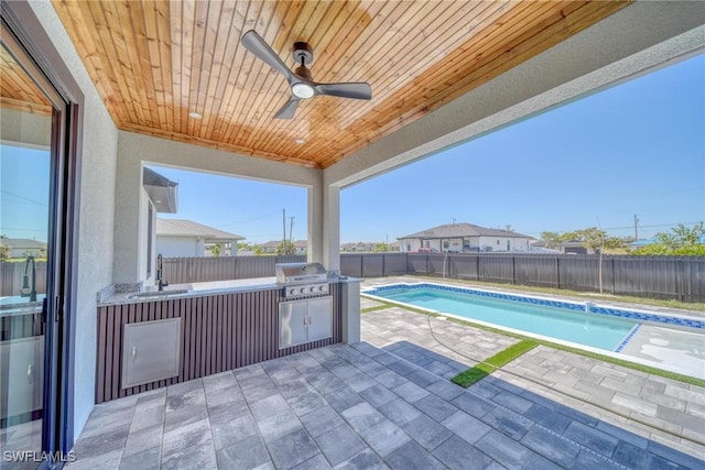 view of swimming pool with a patio, an outdoor kitchen, a grill, a sink, and a fenced backyard