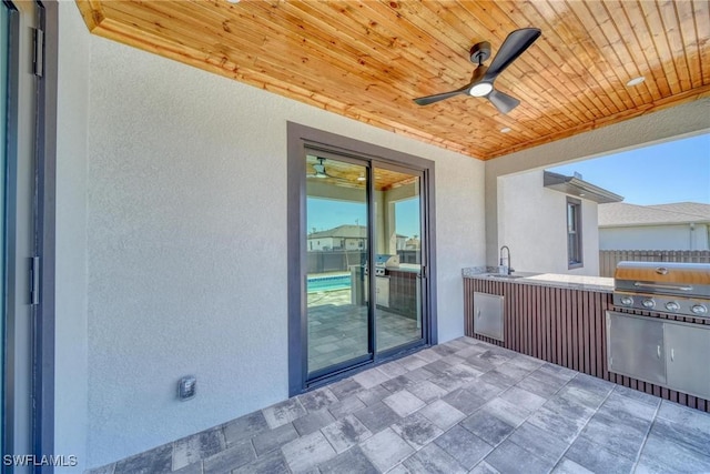 view of patio / terrace featuring ceiling fan, an outdoor kitchen, a sink, fence, and grilling area