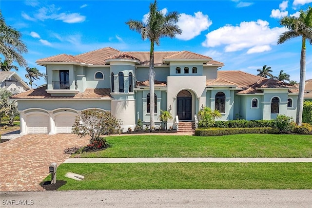 mediterranean / spanish-style house featuring stucco siding, decorative driveway, a balcony, and a front yard