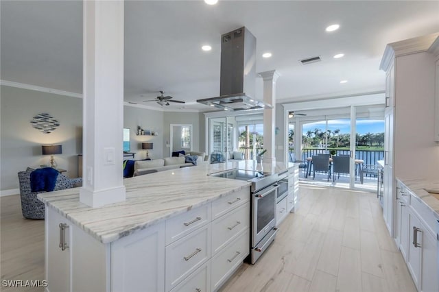 kitchen with island exhaust hood, ornamental molding, open floor plan, and high end stainless steel range