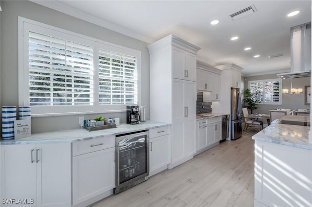 kitchen featuring wine cooler, light wood-style flooring, stainless steel appliances, visible vents, and white cabinets