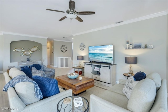 living room featuring baseboards, visible vents, a ceiling fan, and crown molding