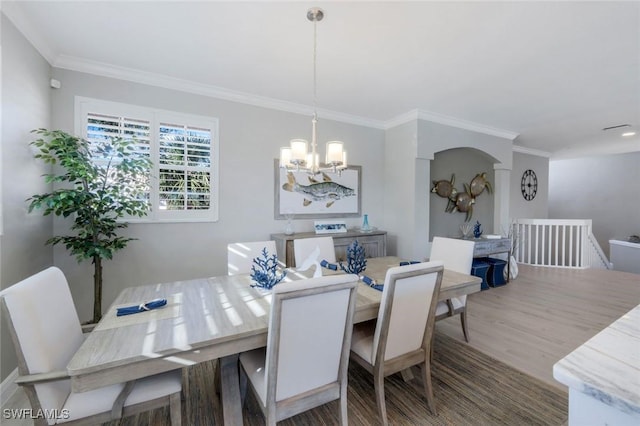 dining area with a chandelier, wood finished floors, and crown molding