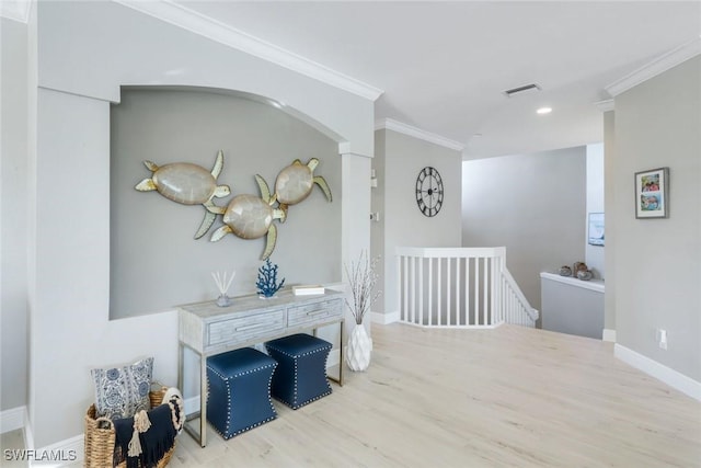 corridor with visible vents, ornamental molding, wood finished floors, and an upstairs landing