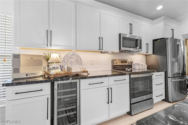 kitchen featuring stainless steel appliances, wine cooler, dark stone counters, white cabinets, and decorative backsplash