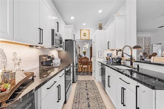 kitchen with tasteful backsplash, ornamental molding, stainless steel appliances, white cabinetry, and a sink