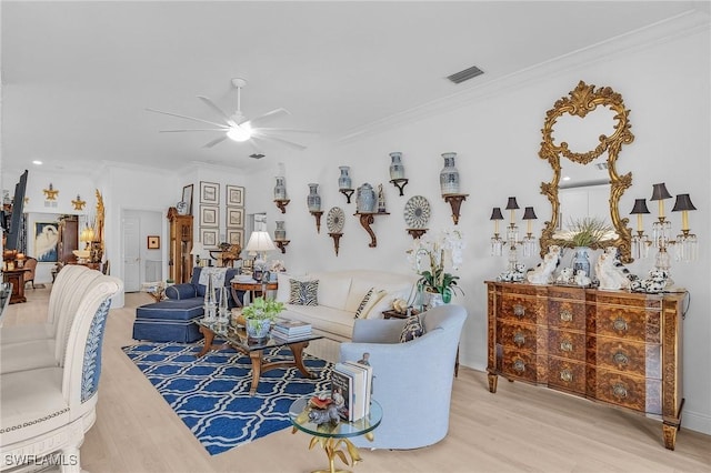 living room with a ceiling fan, wood finished floors, visible vents, and ornamental molding