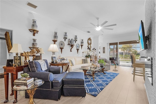 living area with crown molding, wood finished floors, visible vents, and ceiling fan