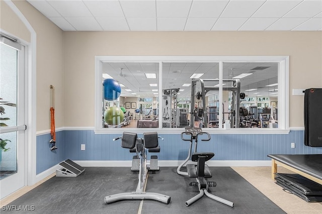 exercise room featuring a wainscoted wall and a paneled ceiling