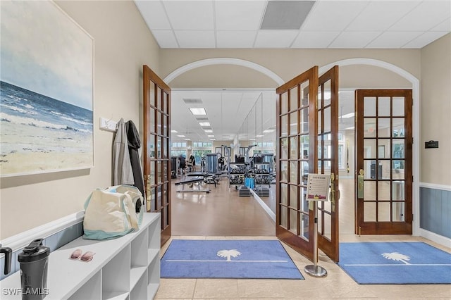 gym with tile patterned flooring, french doors, and a paneled ceiling