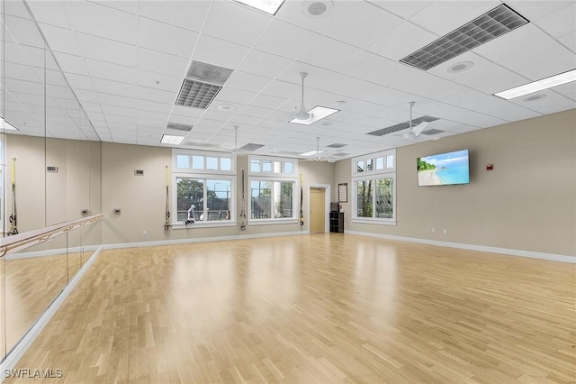 unfurnished room with baseboards, light wood-type flooring, and a paneled ceiling