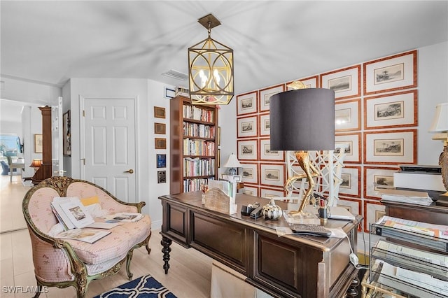 office area with decorative columns, light wood-style floors, visible vents, and an inviting chandelier