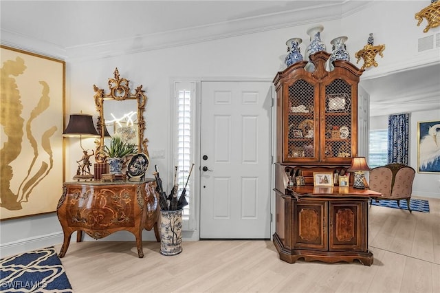 entrance foyer featuring light wood-type flooring, visible vents, baseboards, and ornamental molding