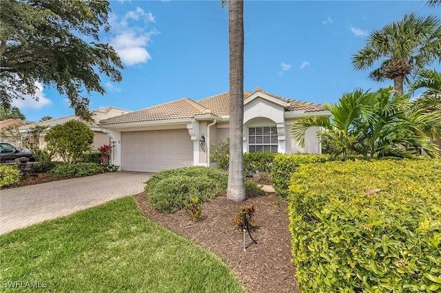 mediterranean / spanish home featuring a garage, decorative driveway, stucco siding, and a tile roof