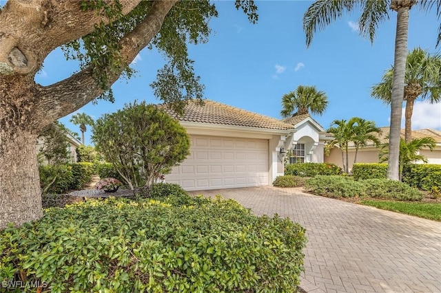 view of front of home with stucco siding, a tile roof, decorative driveway, and a garage