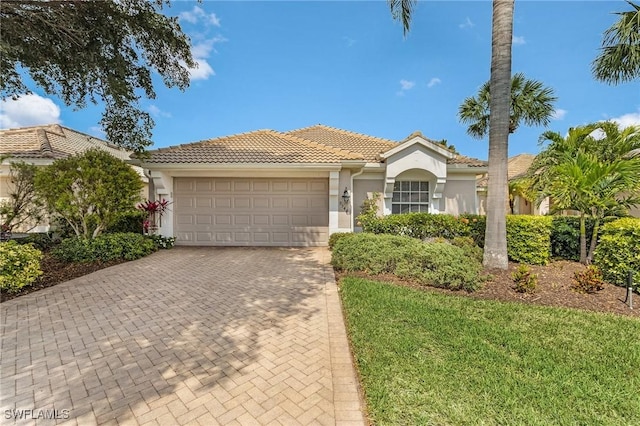 mediterranean / spanish home with stucco siding, a tile roof, decorative driveway, and a garage