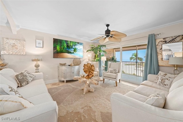 living room with crown molding, baseboards, and a ceiling fan