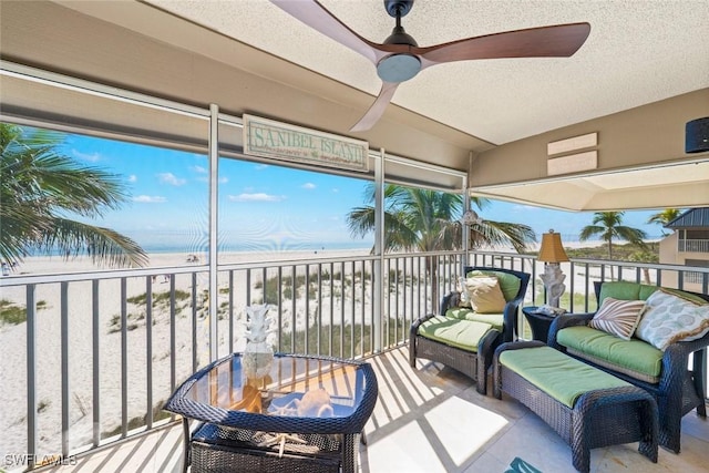 sunroom with a beach view and a ceiling fan