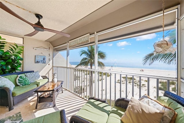 sunroom / solarium featuring a water view, a beach view, and a ceiling fan