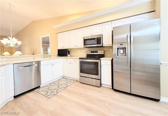 kitchen featuring light wood-style flooring, stainless steel appliances, white cabinetry, vaulted ceiling, and an inviting chandelier